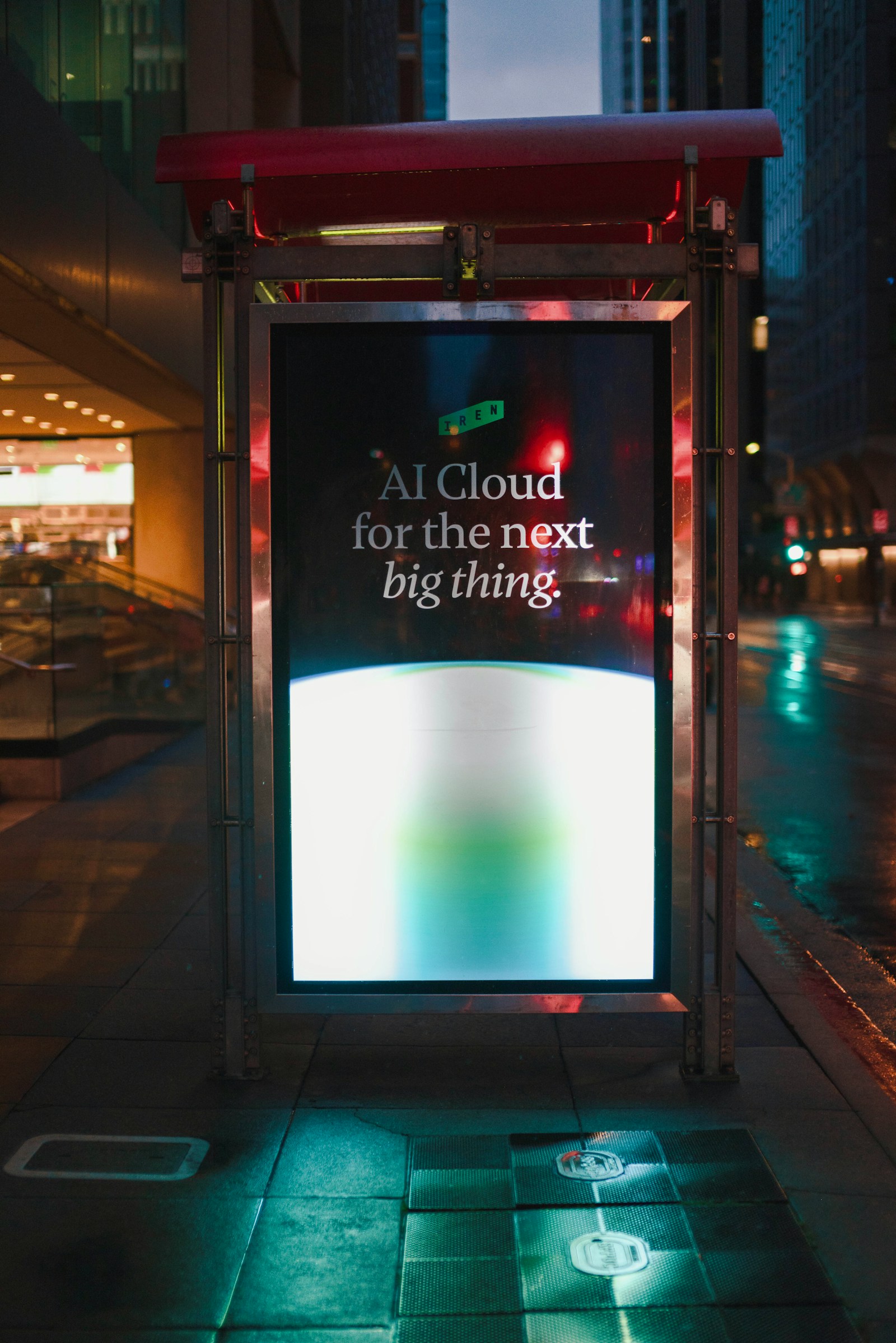 Street-level digital advertising panel in a city at night
